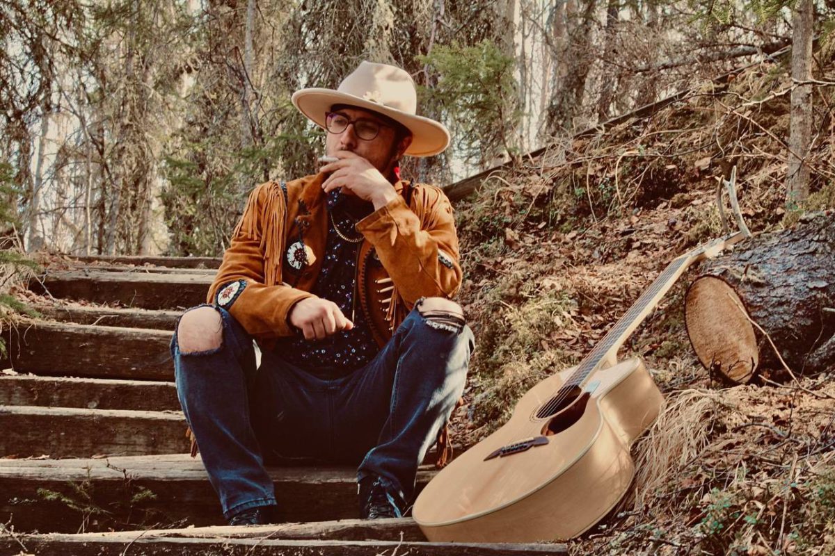 Singer-songwriter Ayden see smoking a cigarette with his guitar in the Alaskan wilderness.